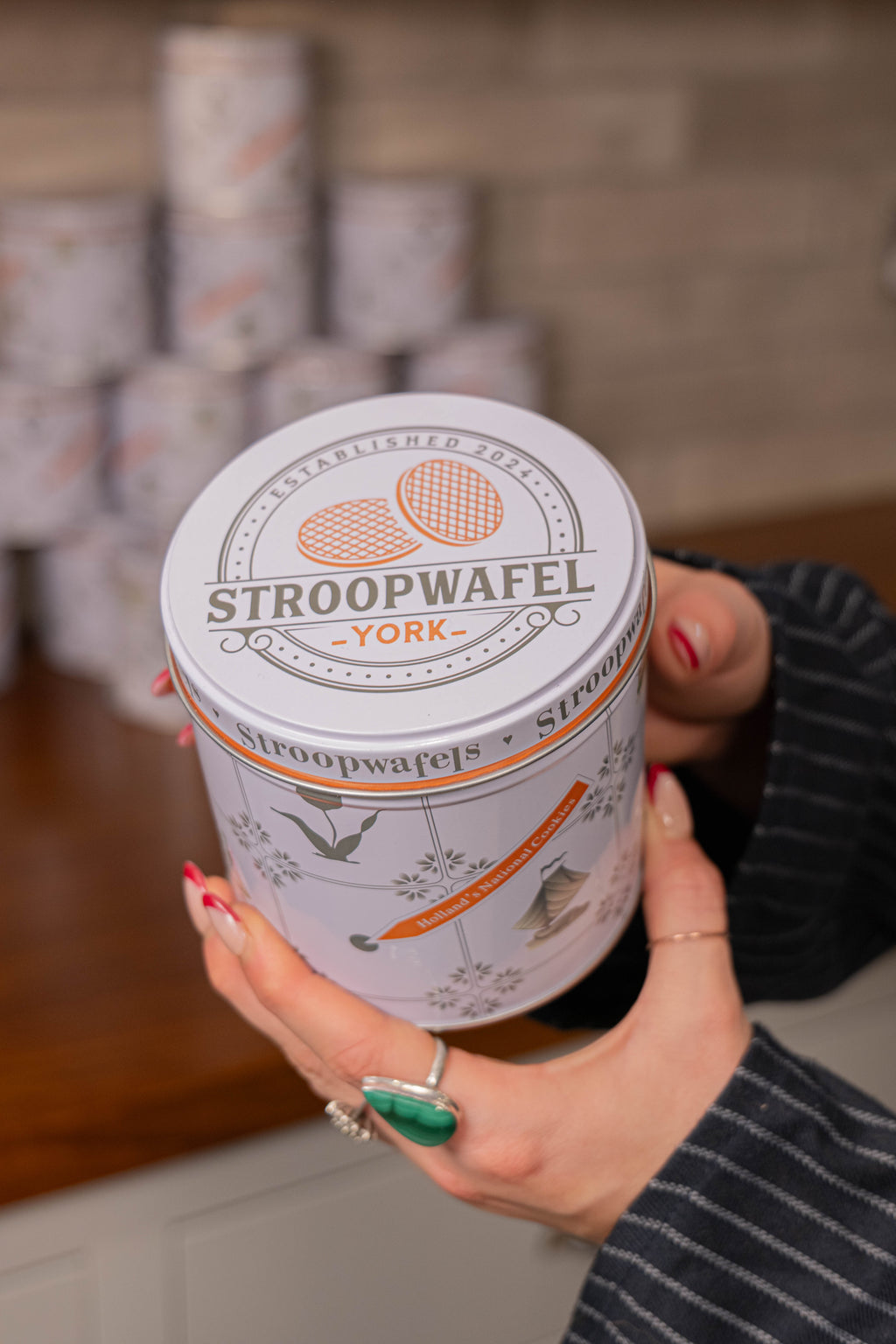 Person holding a can of Stroopwafel York with stacked cans in the background.